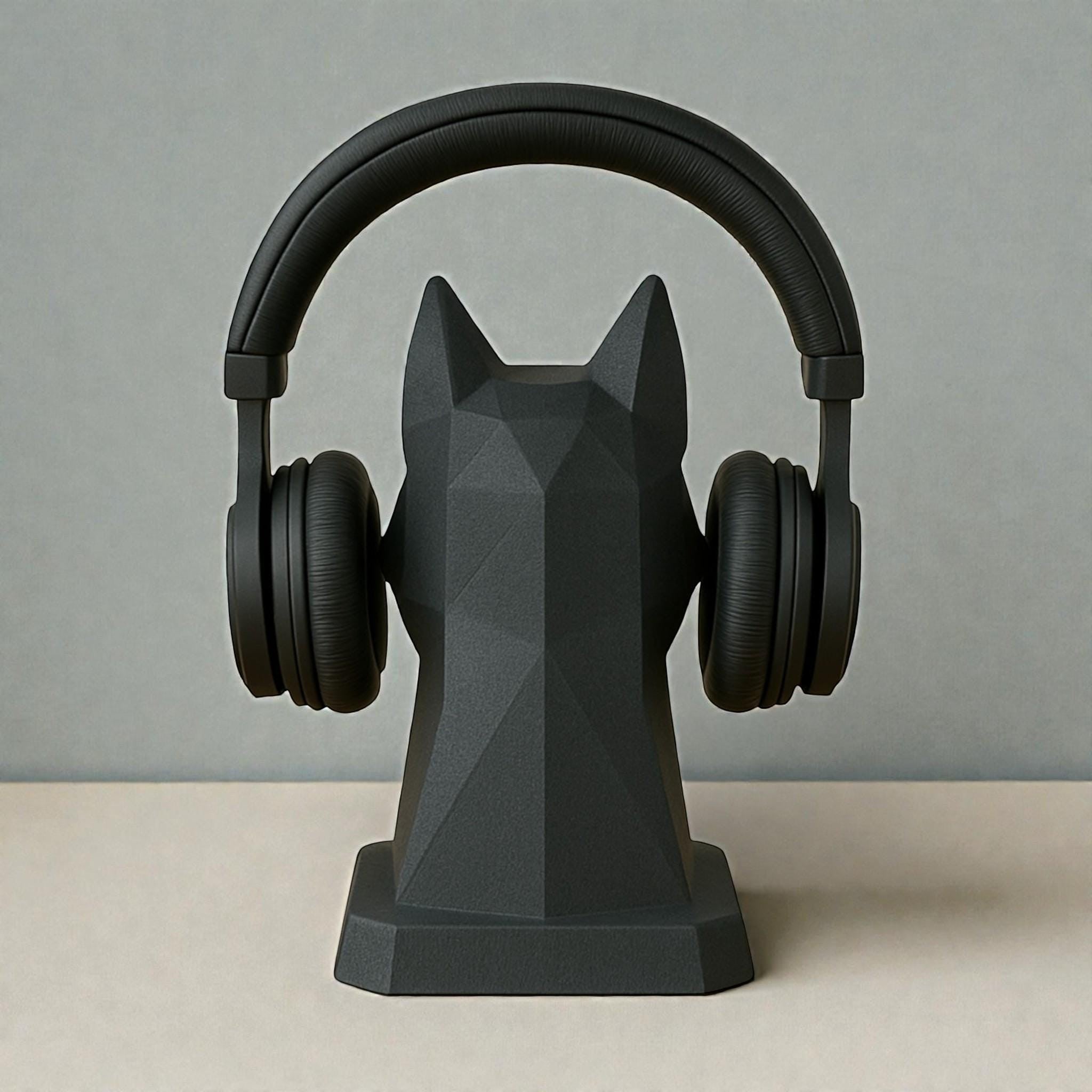 Happy3dWorld black geometric dog headphone stand in a low-poly origami style holding over-ear headphones on a desk.