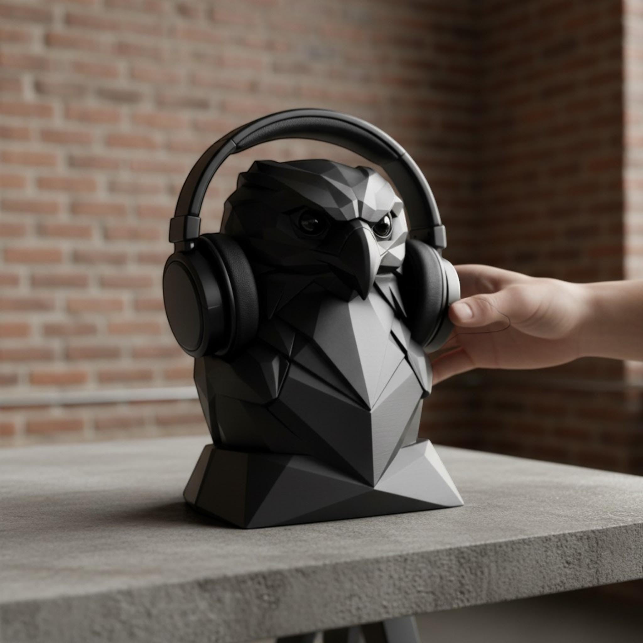 Happy3dWorld black geometric eagle headphone stand with a low-poly faceted design holding over-ear headphones on a desk.