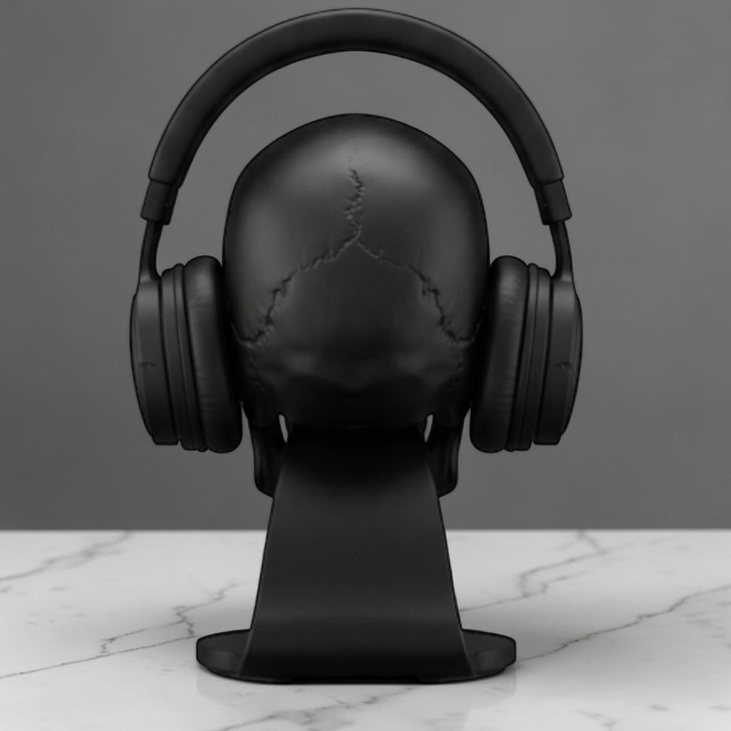 Happy3dWorld matte black anatomical skull headset stand holding over-ear headphones on a white marble desk surface