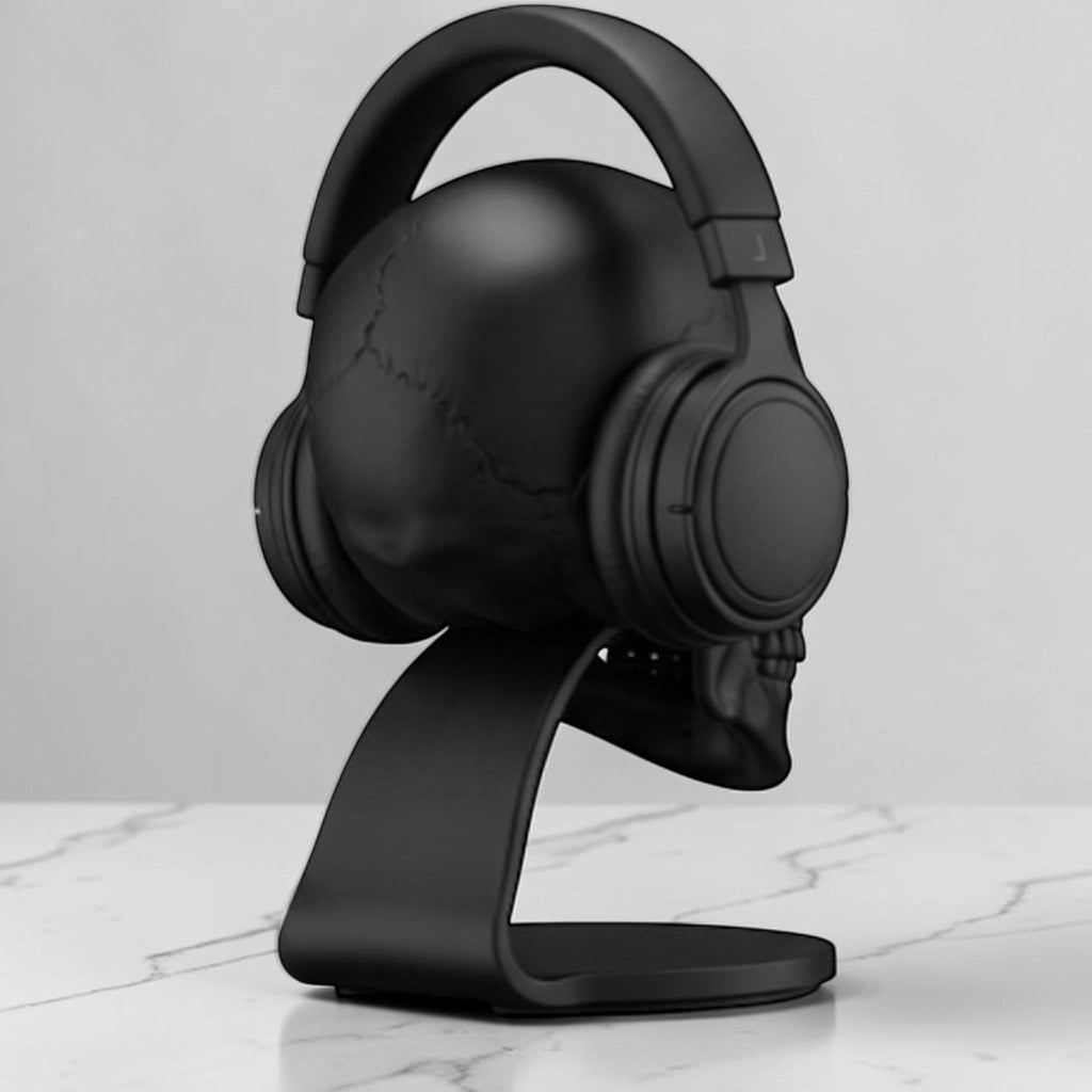 Happy3dWorld matte black anatomical skull headset stand holding over-ear headphones on a marble desk surface.