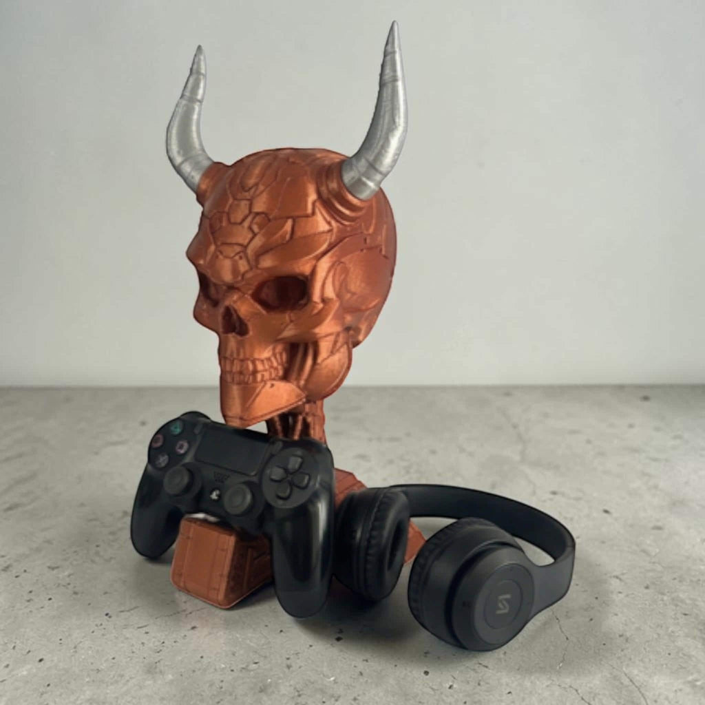 Happy3dWorld cyberpunk skull headset and controller stand in metallic copper with silver horns on a grey desk.