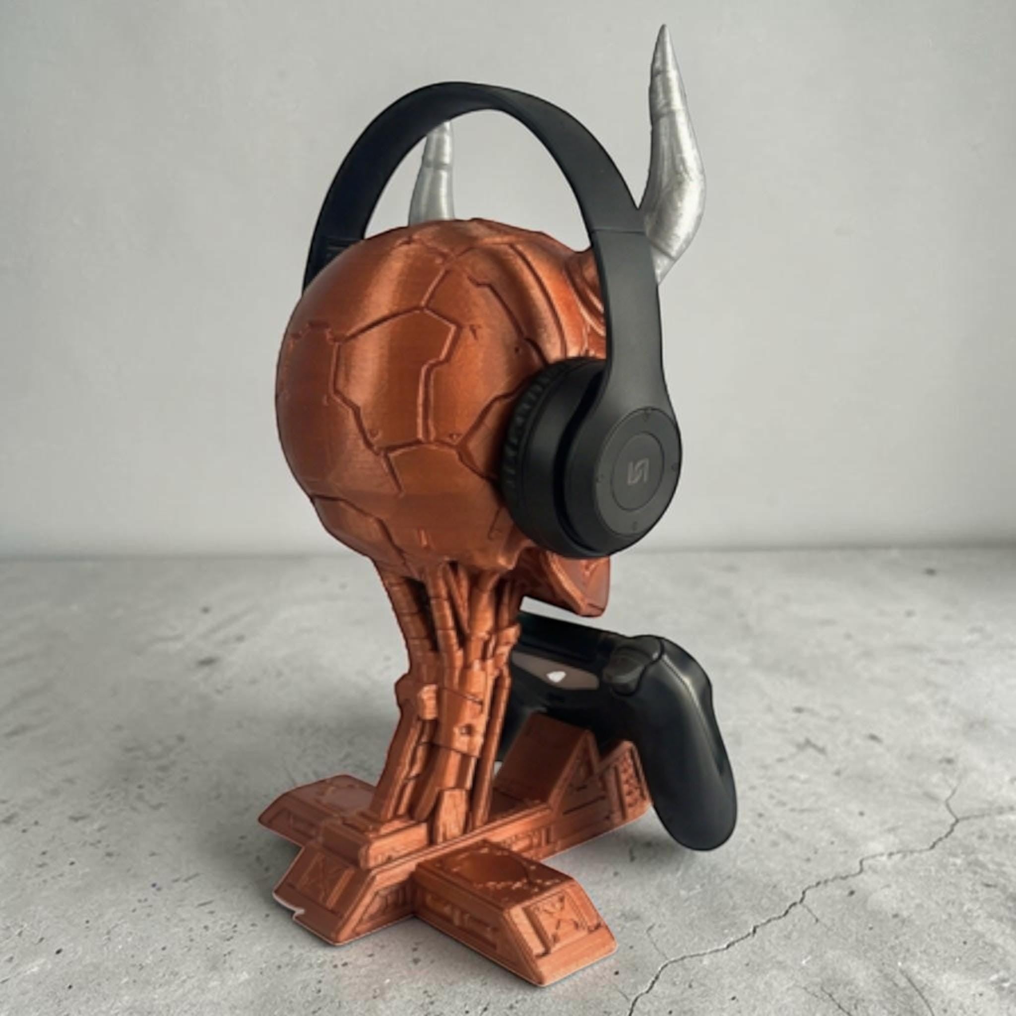 Happy3dWorld cyberpunk skull headset and controller stand in metallic copper with silver horns on a grey surface.