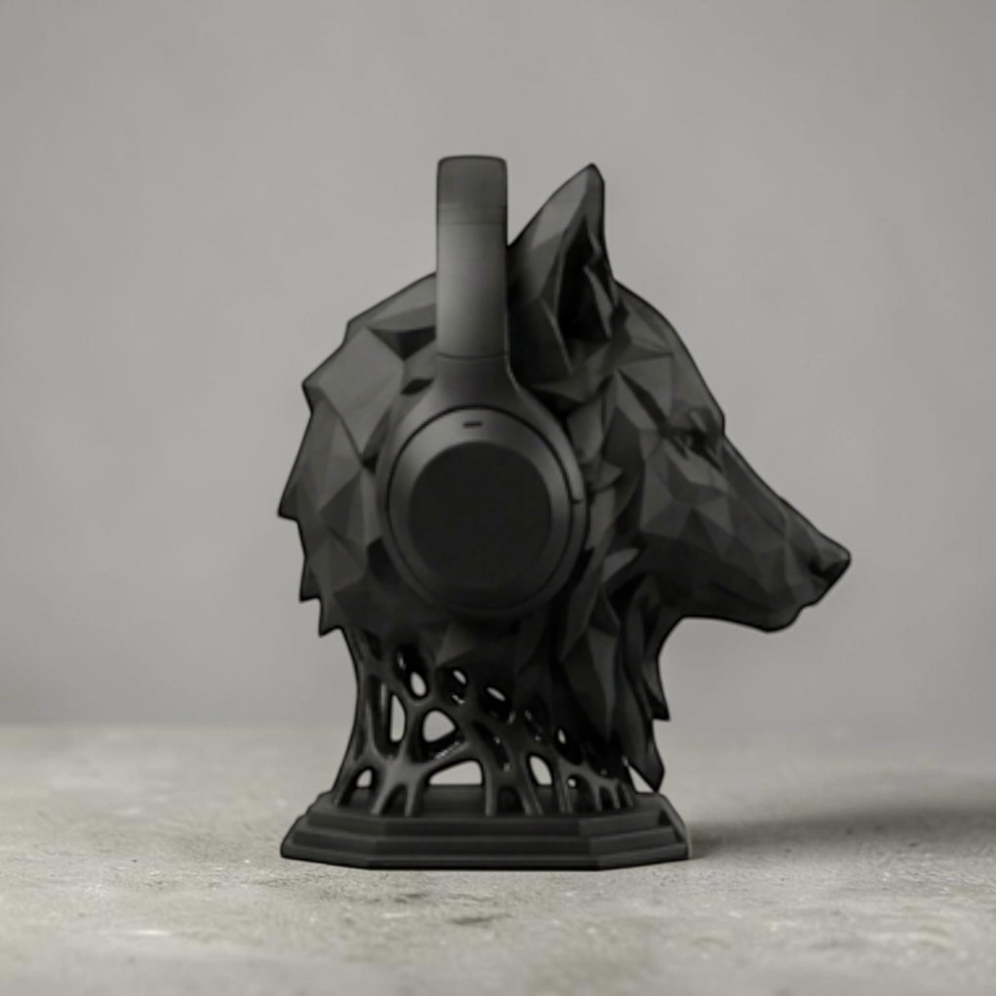 Happy3dWorld matte black geometric wolf head headphone stand holding over-ear headphones on a desk.
