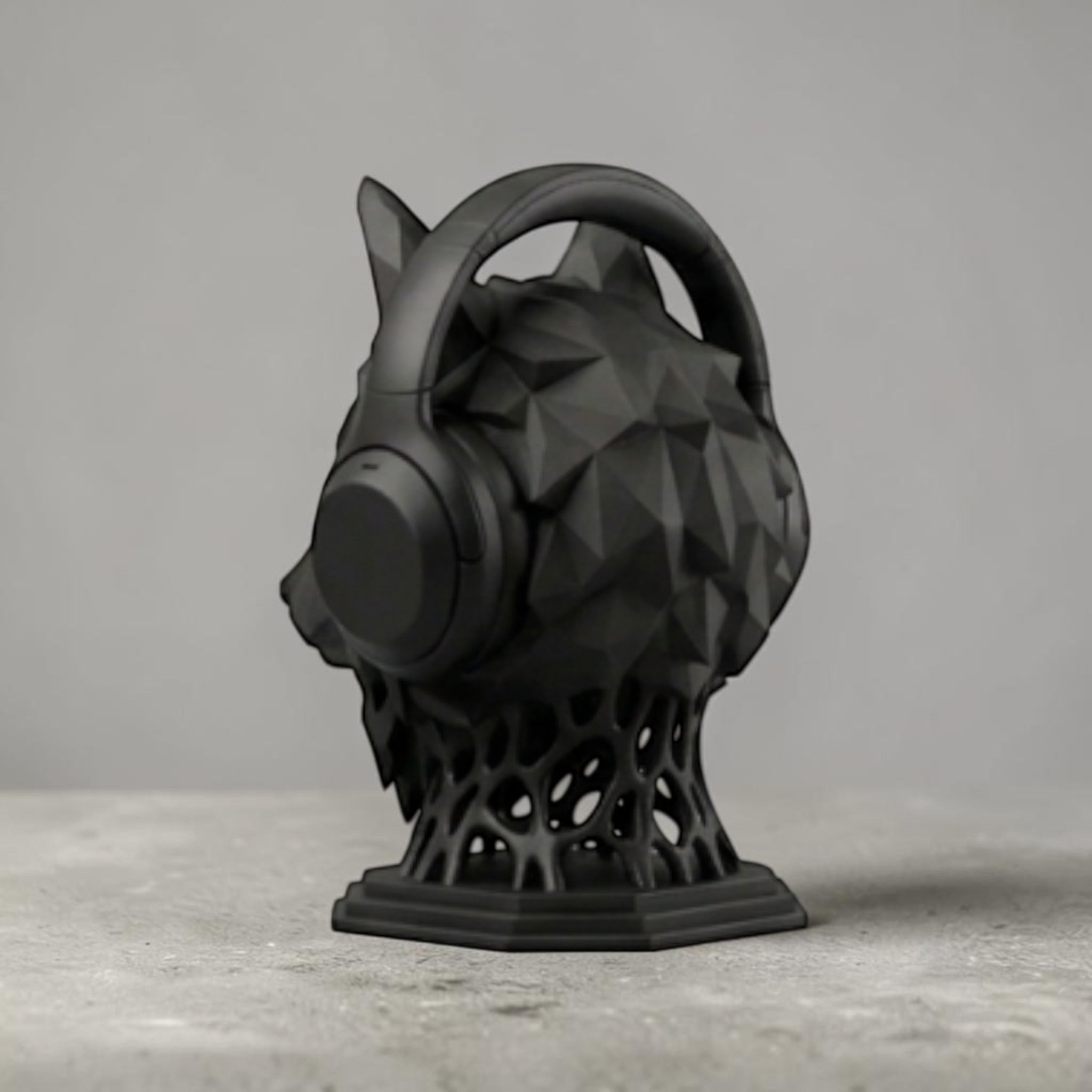 Happy3dWorld matte black geometric wolf head headphone stand with a low-poly design on a grey surface.