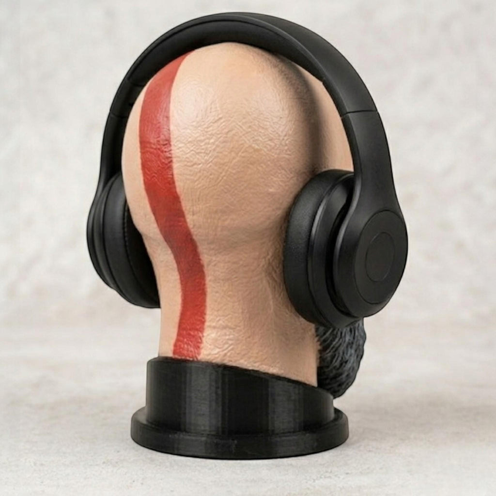 Happy3dWorld Kratos bust headset stand with a red tattoo stripe, holding black gaming headphones on a desk