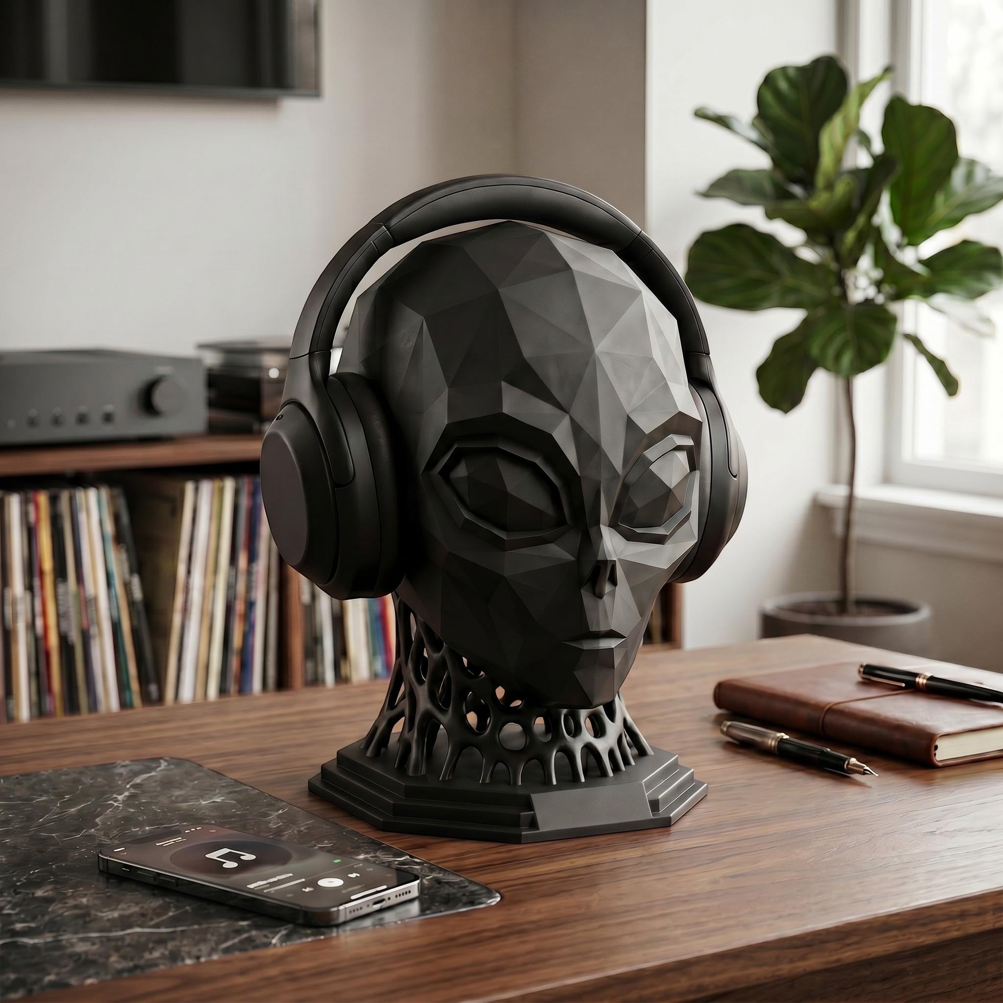 Happy3dWorld matte black low-poly alien headphone stand with a voronoi neck on a wooden desk with headphones.