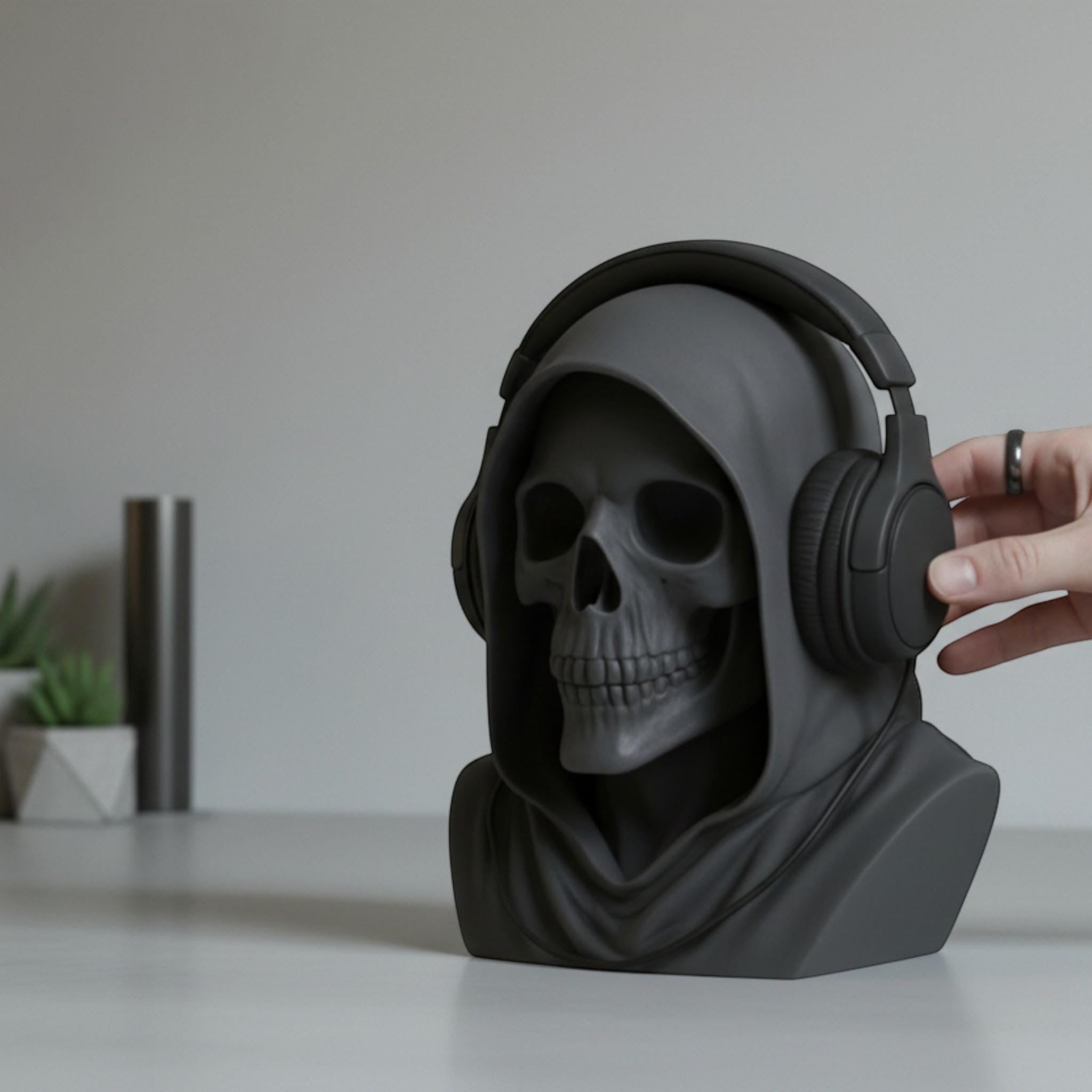 Happy3dWorld matte black death angel skull headphone stand with a hooded design on a desk with headphones
