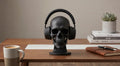 Happy3dWorld matte black anatomical skull headset stand holding over-ear headphones on a wooden desk