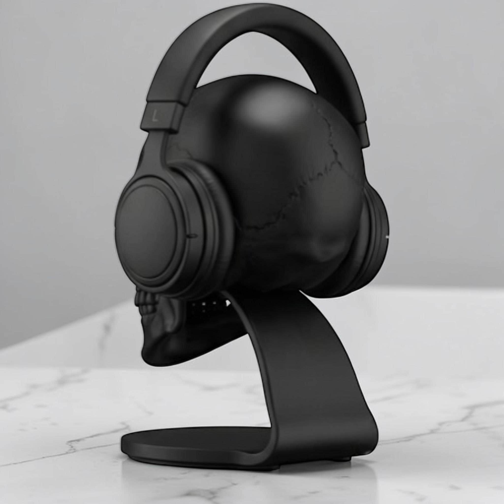 Happy3dWorld matte black anatomical skull headset stand holding over-ear headphones on a white marble desk surface