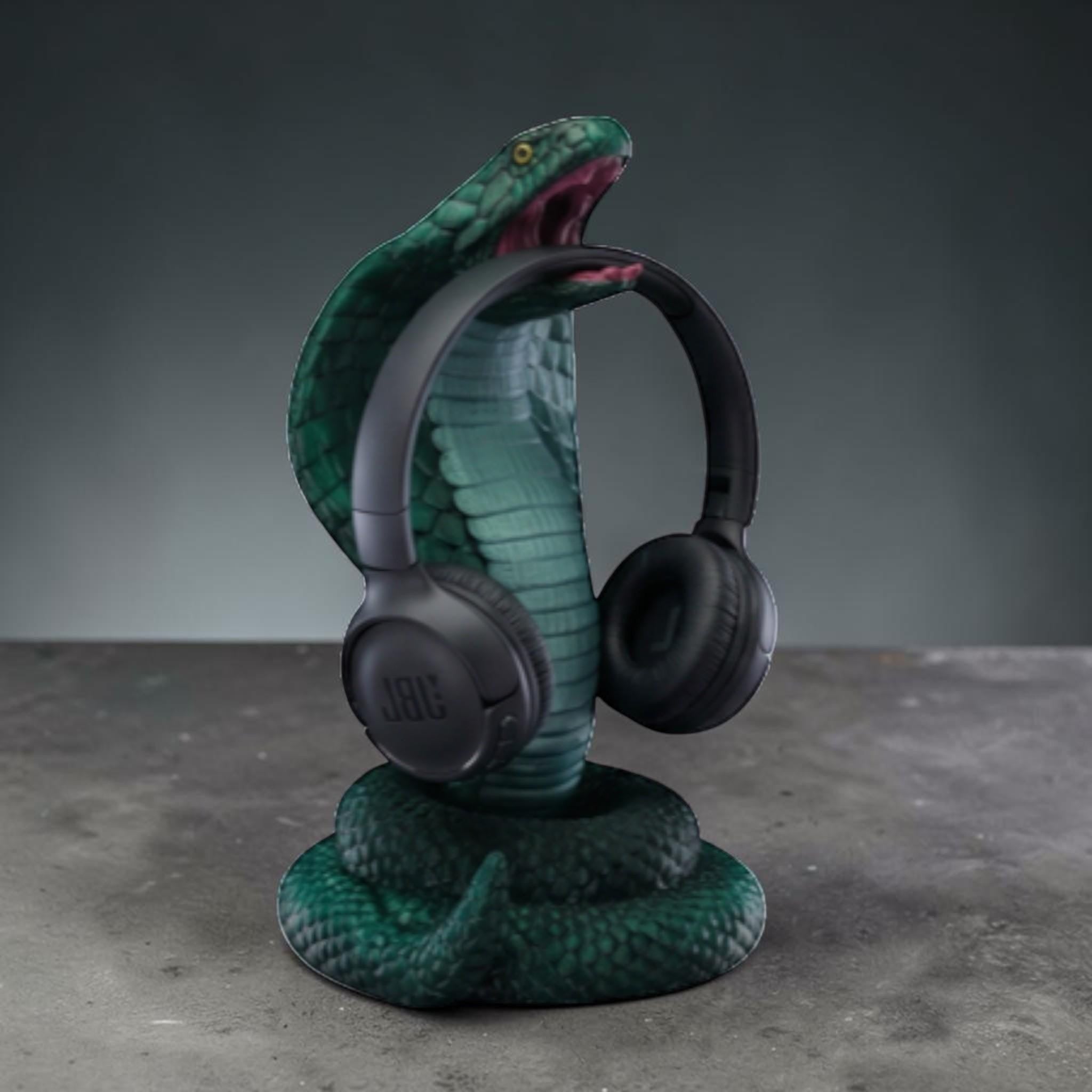 Happy3dWorld metallic green 3D printed cobra headphone hanger holding black over-ear headphones on a desk