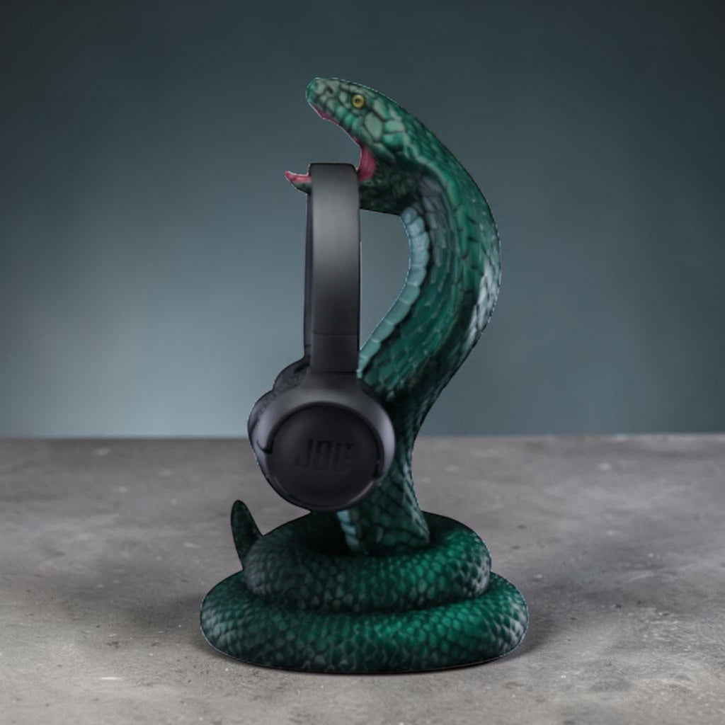 Happy3dWorld metallic green 3D printed cobra snake headphone stand holding black over-ear headphones on a desk.