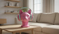 Happy3dWorld pink geometric cat headphone stand with pastel over-ear headphones on a wooden desk in a bright room.
