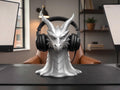 Happy3dWorld silver dragon head headphone stand holding black over-ear headset on a desk in a home office setting