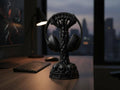 Happy3dWorld matte black gothic skull column headphone stand on a wooden desk in a dark gaming room setting.