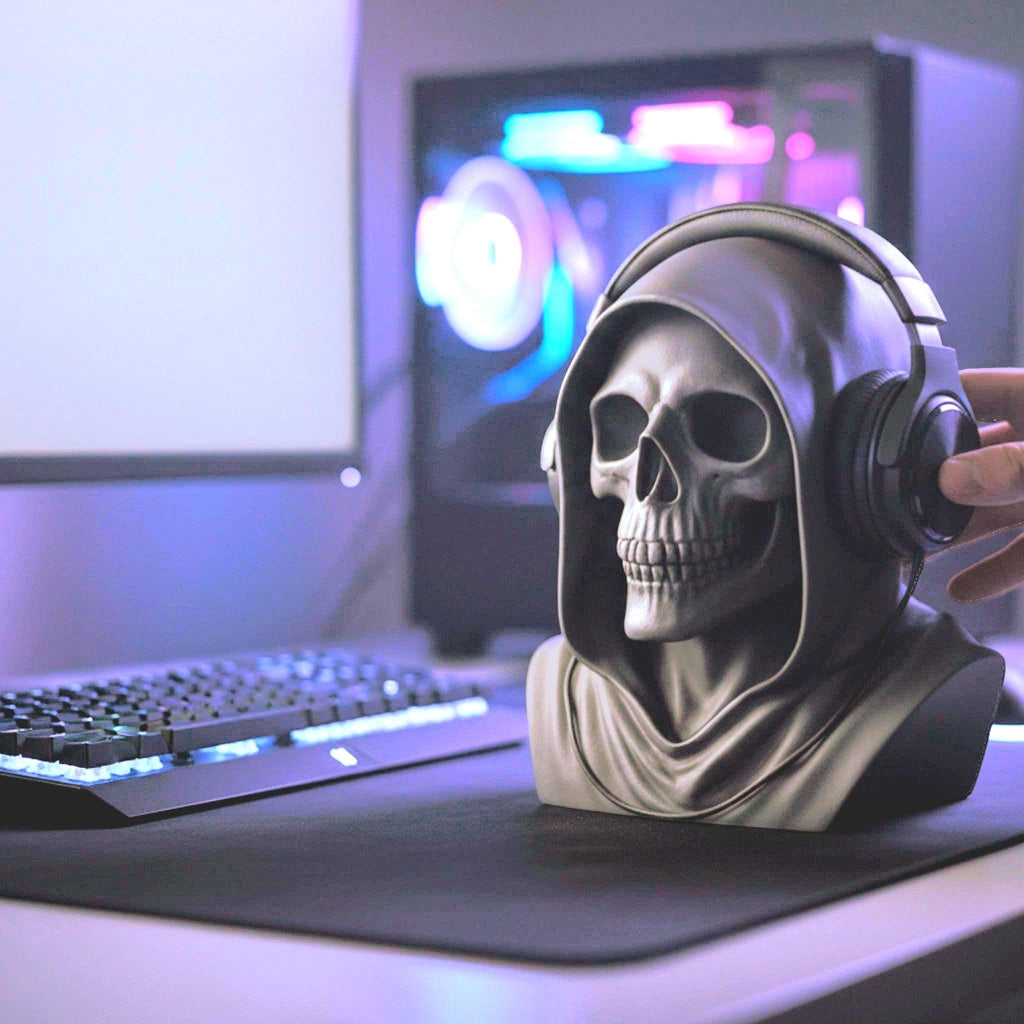 Happy3dWorld matte black death angel skull headphone stand on a gaming desk with keyboard and PC monitor in background