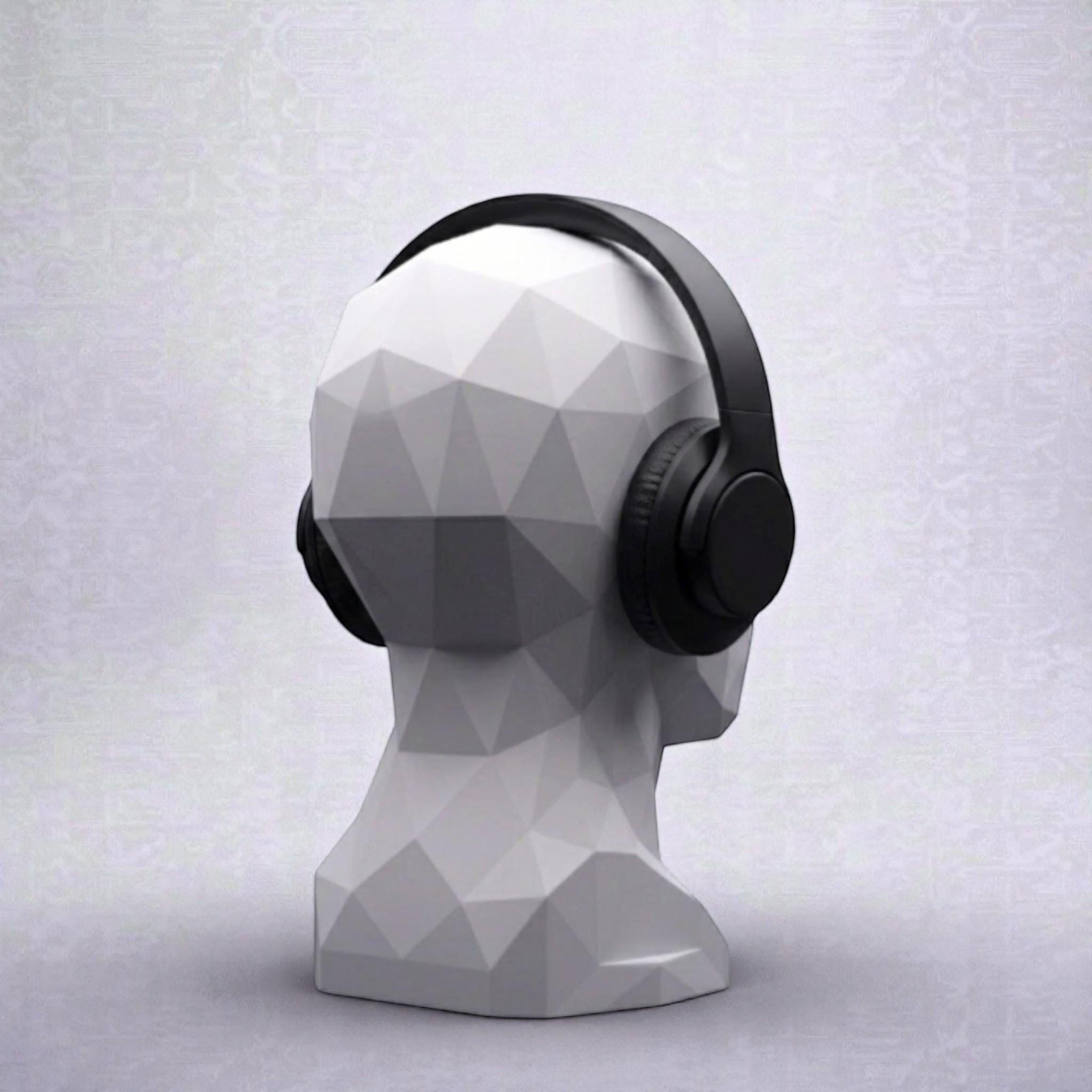 Happy3dWorld white geometric human bust headphone stand displaying black over-ear headphones on a desk